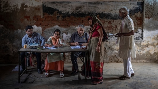 A polling official checks the name of a woman before letting her vote during the third phase of voting in Agra, Uttar Pradesh(AP)