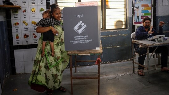 A woman with her child votes inside a polling station in Ahmedabad, Gujarat.(Reuters)