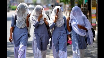 School students use a dupatta to shield themselves from the sun's rays while heading to school for their afternoon shift in Ludhiana on Wednesday. (Manish/HT)