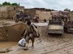An Afghan man carries his belongings as he walks through a mud covered street following a flash flood after a heavy rainfall in Laqiha village of Baghlan-i-Markazi district in Baghlan province