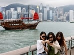 Tourists take photos in front of Victoria Harbour, in Tsim Sha Tsui, in Hong Kong, China. Hong Kong tourism boost: Eight more Chinese cities join solo travel scheme 