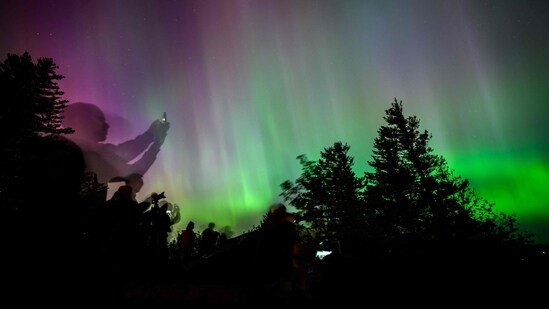 Onlookers gaze upon and photograph the Northern Lights at Chanticleer Point Lookout on the Columbia River Gorge in the early morning hours of May 11 in Latourell, Oregon.(AFP)
