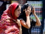 Women cover themselves to protect from the sun on a hot summer day
