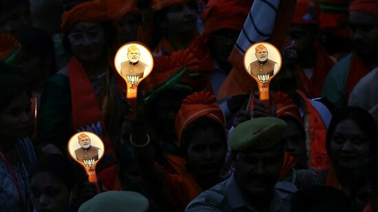 Supporters of Bharatiya Janata Party (BJP) holding campaign materials with pictures of India's Prime Minister Narendra Modi take part in a roadshow, in Varanasi on May 13, 2024, during ongoing India's general election. ( (Photo by Niharika KULKARNI / AFP))