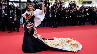 Aishwarya Rai posed for photographers at the premiere of the film Megalopolis at the 77th Cannes Film Festival. She attended the red carpet of the event in a black and gold gown adorned with intricate golden patterns. Her attire, designed by Falguni and Shane, featured a long train embellished with opulent golden flowers. (AFP) Aishwarya Rai posed for photographers at the premiere of the film Megalopolis at the 77th Cannes Film Festival. She attended the red carpet of the event in a black and gold gown adorned with intricate golden patterns. Her attire, designed by Falguni and Shane, featured a long train embellished with opulent golden flowers. (AFP)