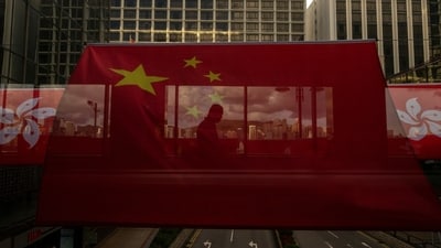 FILE- A pedestrian walks through a footbridge is silhouetted as Chinese and Hong Kong flags are strung to mark the 26th anniversary of the city's handover from Britain to China in Hong Kong, on June 27, 2023. Hong Kong’s plan to enact a new national security law, on top of a sweeping legislation that was imposed by Beijing and used to crack down on dissent, is deepening concerns over the erosion of freedoms in the former British colony.(AP Photo/Louise Delmotte, File) (AP) FILE- A pedestrian walks through a footbridge is silhouetted as Chinese and Hong Kong flags are strung to mark the 26th anniversary of the city's handover from Britain to China in Hong Kong, on June 27, 2023. Hong Kong’s plan to enact a new national security law, on top of a sweeping legislation that was imposed by Beijing and used to crack down on dissent, is deepening concerns over the erosion of freedoms in the former British colony.(AP Photo/Louise Delmotte, File) (AP)