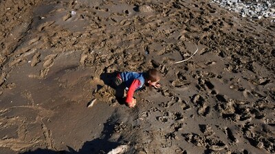 A child crawls on mud after floods in Burka district of Baghlan province. (AFP)