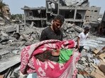 A man carries the dead body of a Palestinian child recovered from a house hit by an Israeli strike, in Nuseirat, in the central Gaza Strip