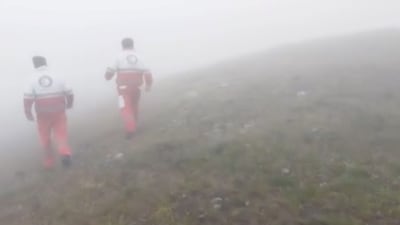 Emergency personnel walk in a foggy area following a crash of a helicopter carrying Iran's President Ebrahim Raisi, in Varzaqan , East Azerbaijan Province, Iran. (via REUTERS)