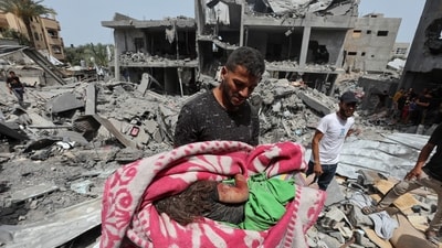 A man carries the dead body of a Palestinian child recovered from a house hit by an Israeli strike, in Nuseirat, in the central Gaza Strip (REUTERS)