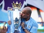 Manchester City's head coach Pep Guardiola celebrates with the Premier League trophy.