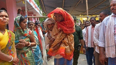 A man carries an elderly voter to cast her ballot at a polling station during the fifth phase of voting in India's general election, in Hajipur on May 20, 2024. (AFP)