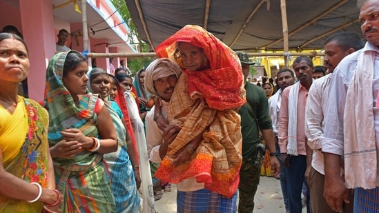 A man carries an elderly voter to cast her ballot at a polling station during the fifth phase of voting in India's general election, in Hajipur on May 20, 2024. (AFP)