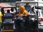 People travelling on an electric rickshaw cover their heads to shelter from the sun during a hot summer day People travelling on an electric rickshaw cover their heads to shelter from the sun during a hot summer day