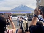 Visitors take a photo in front of a convenient store at Fujikawaguchiko town, Yamanashi prefecture, Japan, with a backdrop of Mt Fuji. (AP)