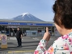 A person takes pictures of Mount Fuji from across the street of a Lawson convenience store, hours before the installation of a barrier to block the sight of Japan's Mount Fuji to deter badly behaved tourists. A person takes pictures of Mount Fuji from across the street of a Lawson convenience store, hours before the installation of a barrier to block the sight of Japan's Mount Fuji to deter badly behaved tourists.