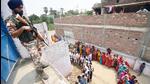 A security official stands guard as people queue up to cast their votes at a polling booth in Saran, Bihar on Monday. (Santosh Kumar/ HT Photo)