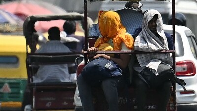 People travelling on an electric rickshaw cover their heads to shelter from the sun during a hot summer day (AFP)