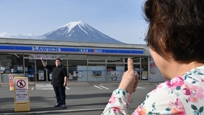 A person takes pictures of Mount Fuji from across the street of a Lawson convenience store, hours before the installation of a barrier to block the sight of Japan's Mount Fuji to deter badly behaved tourists. (AFP) A person takes pictures of Mount Fuji from across the street of a Lawson convenience store, hours before the installation of a barrier to block the sight of Japan's Mount Fuji to deter badly behaved tourists. (AFP)