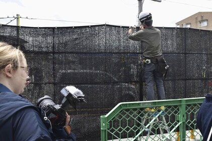 A worker sets up a huge black screen on a stretch of sidewalk at Fujikawaguchiko town, Yamanashi prefecture, central Japan Tuesday, May 21, 2024. (AP) A worker sets up a huge black screen on a stretch of sidewalk at Fujikawaguchiko town, Yamanashi prefecture, central Japan Tuesday, May 21, 2024. (AP)