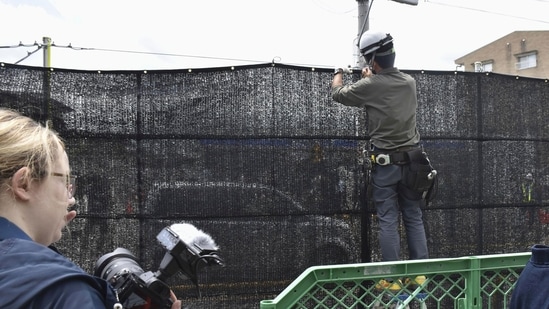 A worker sets up a huge black screen on a stretch of sidewalk at Fujikawaguchiko town, Yamanashi prefecture, central Japan Tuesday, May 21, 2024. (AP) A worker sets up a huge black screen on a stretch of sidewalk at Fujikawaguchiko town, Yamanashi prefecture, central Japan Tuesday, May 21, 2024. (AP)