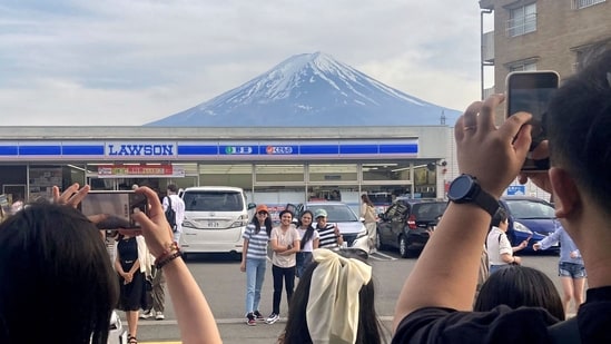 Visitors take a photo in front of a convenient store at Fujikawaguchiko town, Yamanashi prefecture, Japan, with a backdrop of Mt Fuji. (AP)