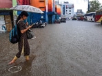 A commuter passes through a waterlogged bus station amid heavy rain in Kochi.
