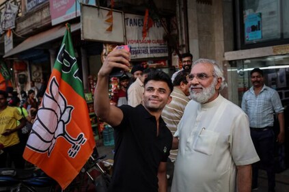 A man takes a picture with Jagdish Rai Bhatia, a real-estate businessman and look-alike of Prime Minister Narendra Modi. A man takes a picture with Jagdish Rai Bhatia, a real-estate businessman and look-alike of Prime Minister Narendra Modi.