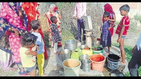 Women and kids line up at a hand-pump in Belhat village of Koraon. (HT)