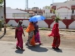 Women take shelter under an umbrella due to extreme heat as they exit a polling booth after casting their vote in Uttar Pradesh. (Reuters photo)