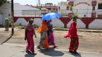 Women take shelter under an umbrella due to extreme heat as they exit a polling booth after casting their vote in Uttar Pradesh. (Reuters photo)