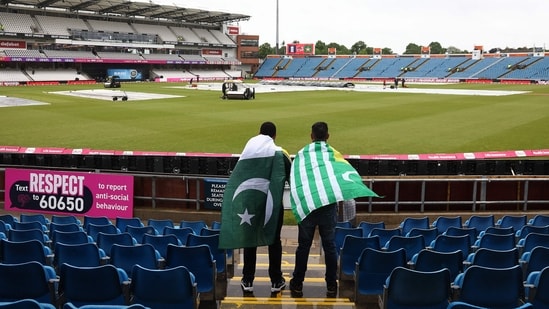 Fans, draped in Pakistan flags, watch as groundstaff attempt to clear rain water from the pitch ahead of the first T20I vs England (AFP)