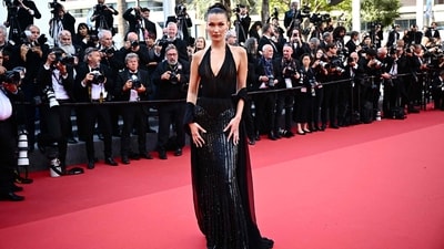 US model Bella Hadid arrives at the 77th edition of the Cannes Film Festival wearing a stunning Atelier Versace Spring/Summer 2001 collection for the screening of the film 'L'Amour Ouf' (Beating Hearts). Her outfit featured a halterneck, plunging neckline, shimmering fabric and a floor-length hem. Hadid paired the stunning dress with a gauzy black scarf, which she draped over her arms, and diamond jewellery. (Photo by LOIC VENANCE / AFP) US model Bella Hadid arrives at the 77th edition of the Cannes Film Festival wearing a stunning Atelier Versace Spring/Summer 2001 collection for the screening of the film 'L'Amour Ouf' (Beating Hearts). Her outfit featured a halterneck, plunging neckline, shimmering fabric and a floor-length hem. Hadid paired the stunning dress with a gauzy black scarf, which she draped over her arms, and diamond jewellery. (Photo by LOIC VENANCE / AFP)