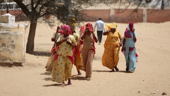 Women cover their faces to protect themselves from heat as they arrive at a polling station to cast their votes during the first phase of the general election in Bikaner district, India, April 19, 2024.