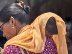 A woman covers her child with a scarf to save him from heat wave on a hot summer day in Mumbai, India, Thursday, May 23, 2024. (AP Photo/Rafiq Maqbool)