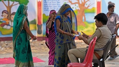 A woman shows her identity card and voter's slip to a policeman outside a polling station as she arrives to cast her vote in the sixth round of polling in Prayagraj on Saturday. (AP) A woman shows her identity card and voter's slip to a policeman outside a polling station as she arrives to cast her vote in the sixth round of polling in Prayagraj on Saturday. (AP)