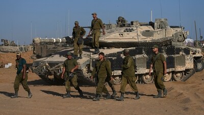 Israeli soldiers walk in a staging area for their tanks near the Gaza border in southern Israel (AP) Israeli soldiers walk in a staging area for their tanks near the Gaza border in southern Israel (AP)