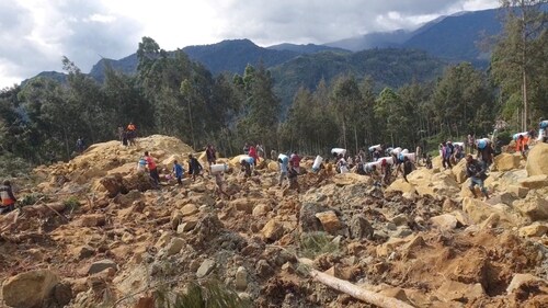 People carry bags in the aftermath of a landslide in Enga Province, Papua New Guinea, May 24, 2024. (Reuters)