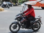 India heatwave: A man rides a motorcycle with a roof to protect himself from a heatwave on the street in Ahmedabad, India.