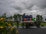 Workers drive their motorised three-wheeler along a road as rain clouds loom over the sky due to the effect of Cyclone Remal Workers drive their motorised three-wheeler along a road as rain clouds loom over the sky due to the effect of Cyclone Remal