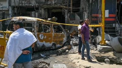 Men gather near the remains of a burnt vehicle at the accident site after fire blazed through a children's hospital in New Delhi on May 26, 2024. (Photo by Arun SANKAR / AFP) Men gather near the remains of a burnt vehicle at the accident site after fire blazed through a children's hospital in New Delhi on May 26, 2024. (Photo by Arun SANKAR / AFP)