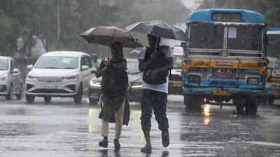 Commuters in Kolkata take cover under umbrellas while crossing roads during rainfall ahead of Cyclone Remal's landfall on Sunday. (PTI) Commuters in Kolkata take cover under umbrellas while crossing roads during rainfall ahead of Cyclone Remal's landfall on Sunday. (PTI)