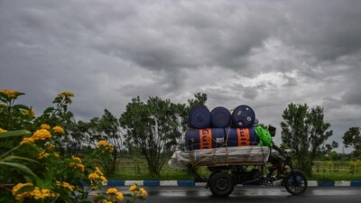 Workers drive their motorised three-wheeler along a road as rain clouds loom over the sky due to the effect of Cyclone Remal (AFP) Workers drive their motorised three-wheeler along a road as rain clouds loom over the sky due to the effect of Cyclone Remal (AFP)