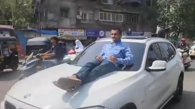 Man lying on the bonnet of BMW driven by a teenager near Mumbai. (X/@BitmanRaj) Man lying on the bonnet of BMW driven by a teenager near Mumbai. (X/@BitmanRaj)