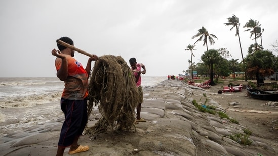 Men move fishing nets as water flows on to the Kuakata beach on the coast of Bay of Bengal. (AP)