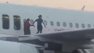 An IndiGo crew helping a passenger walk on the plane's wing after coming out of the emergency exit. (X/@ANI) An IndiGo crew helping a passenger walk on the plane's wing after coming out of the emergency exit. (X/@ANI)