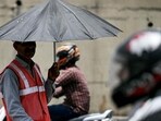 A toll booth worker (left) directing traffic takes shade under an umbrella on a hot summer afternoon in New Delhi on Wednesday. (AFP) A toll booth worker (left) directing traffic takes shade under an umbrella on a hot summer afternoon in New Delhi on Wednesday. (AFP)
