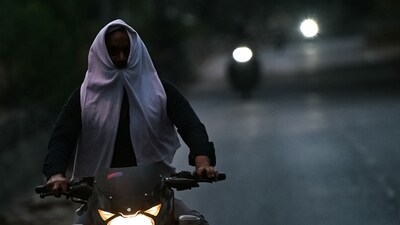 A man riding a motocycle covers his face with cloth on a hot summer evening near Mungeshpur, a suburb in New Delhi. (AFP)