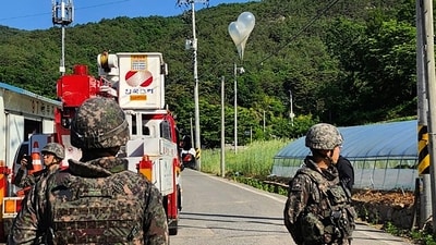 In this photo provided by Jeonbuk Fire Headquarters, balloons with trash presumably sent by North Korea, hang on electric wires as South Korean army soldiers stand guard in Muju, South Korea, (AP) In this photo provided by Jeonbuk Fire Headquarters, balloons with trash presumably sent by North Korea, hang on electric wires as South Korean army soldiers stand guard in Muju, South Korea, (AP)