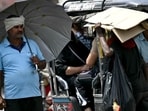 A man takes shelter under an umbrella from the scorching sun on a hot summer afternoon in New Delhi.
